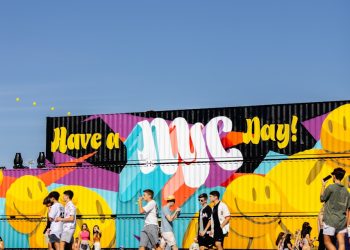 a group of people walking in front of a colorful wall