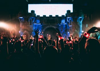 crowded people wearing LED bracelet raising hands in front of stage