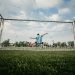 boy in blue shirt playing soccer during daytime